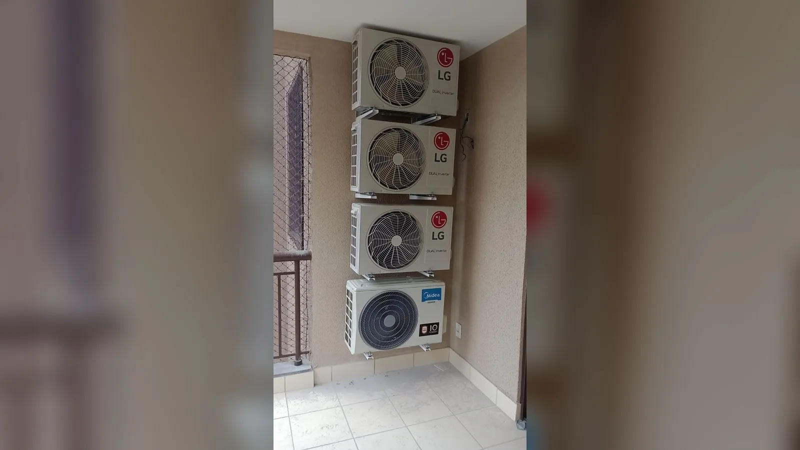 Quatro condensadoras empilhadas em suportes na parede de uma varanda